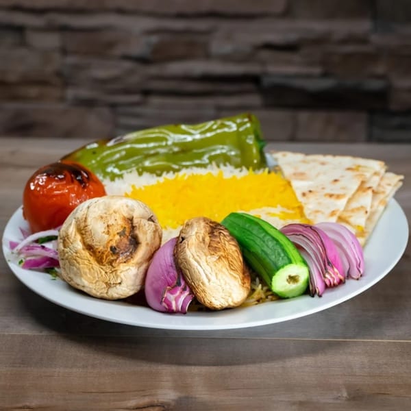 A Mediterranean dish with yellow rice, grilled vegetables, and pita bread on a white plate.
